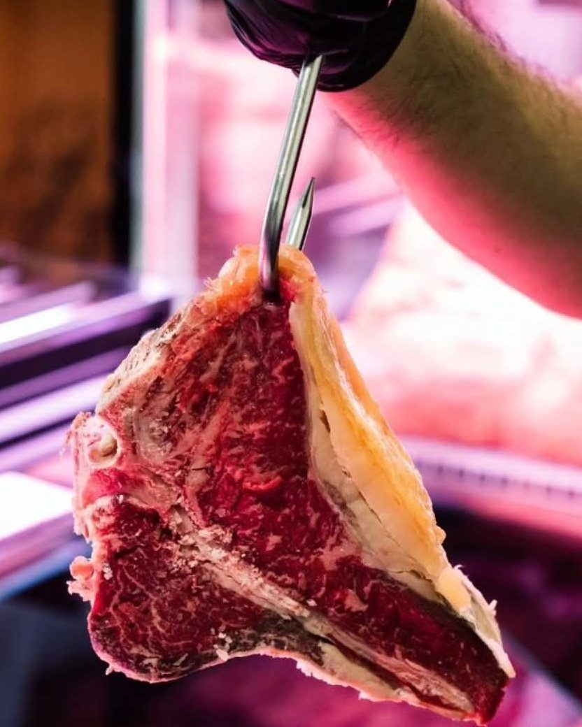 Fiorentina con l’osso appesa al gancio davanti alla vetrina